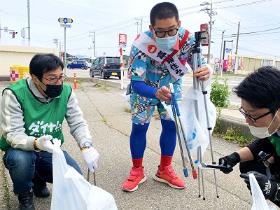 ノビ山本さんと一緒にゴミを拾うダイナム氷見店従業員